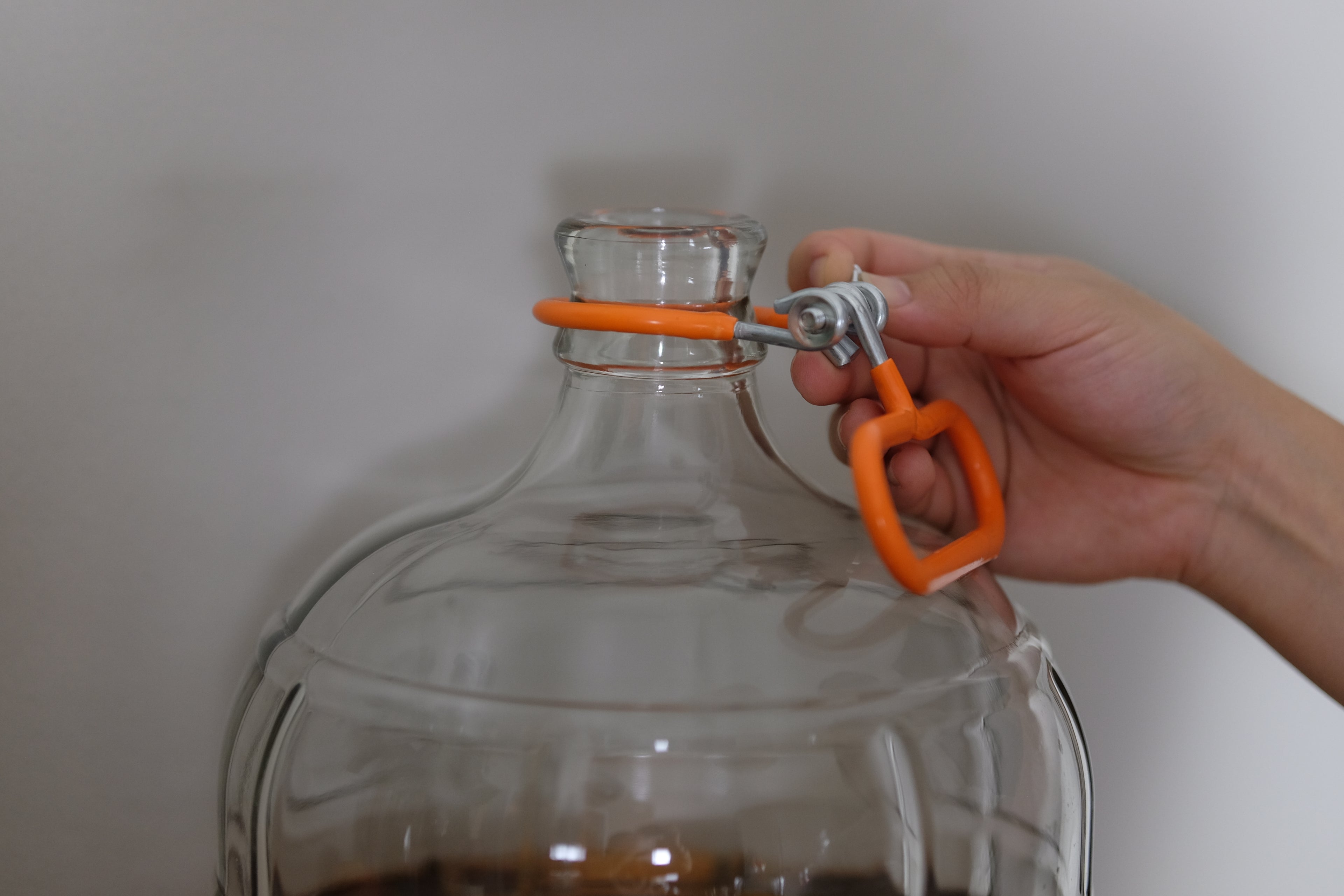Orange carboy neck handle carrier by FastRack, a durable accessory for easy transport of glass carboys.
