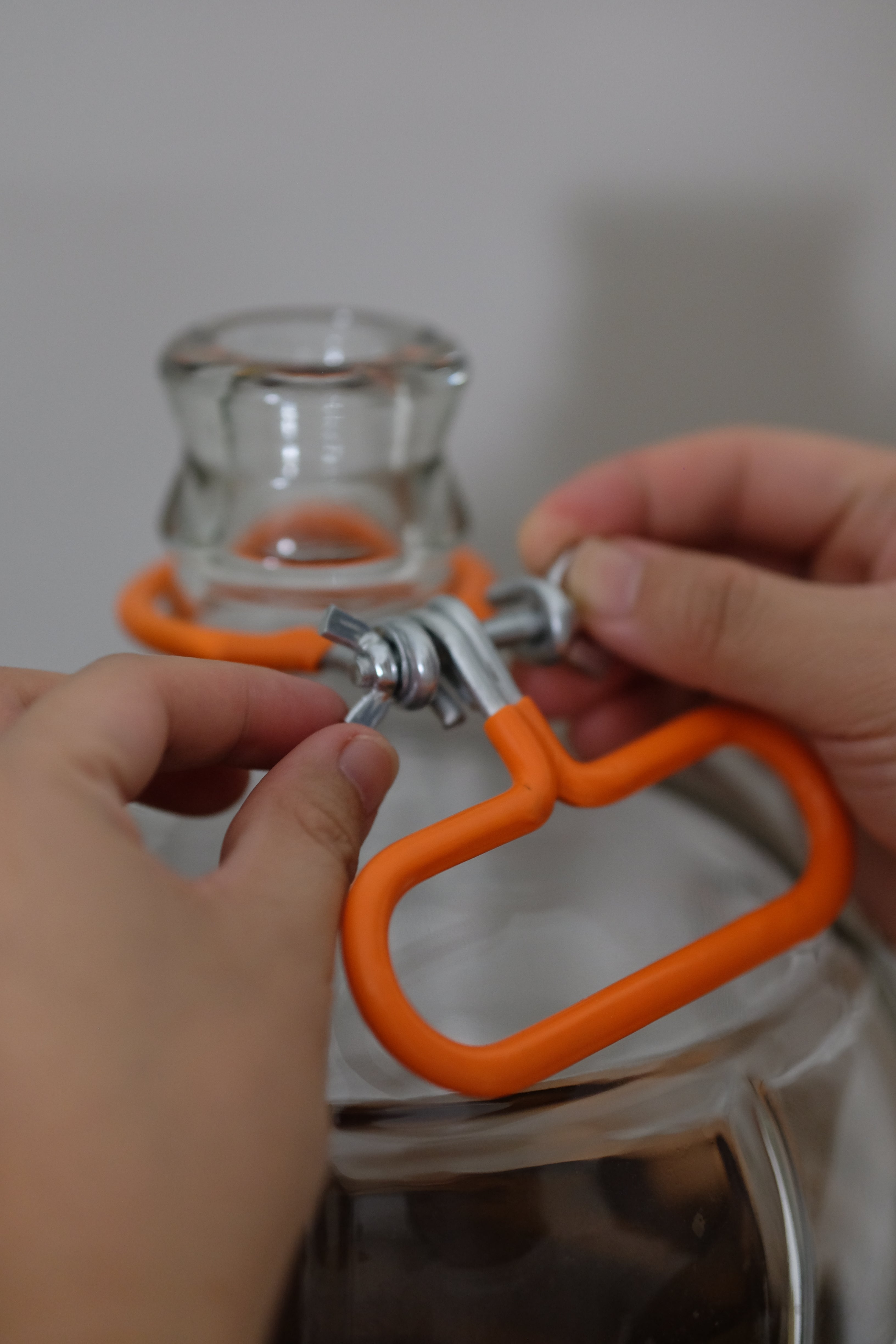 Orange FastRack carboy neck handle carrier with ergonomic grip and secure straps for easy transport of glass carboys.